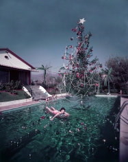 Slim Aarons, Christmas Swim, 1954: Rita Aarons swimming in a pool festooned with floating baubles and a decorated Christmas tree, Hollywood, California