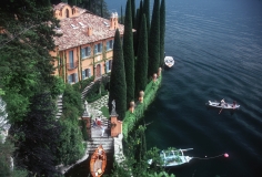 Slim Aarons, Giacomo and Stefania Montegazza welcome guests arriving by boat at their villa, La Casinella, on Lake Como, 1983